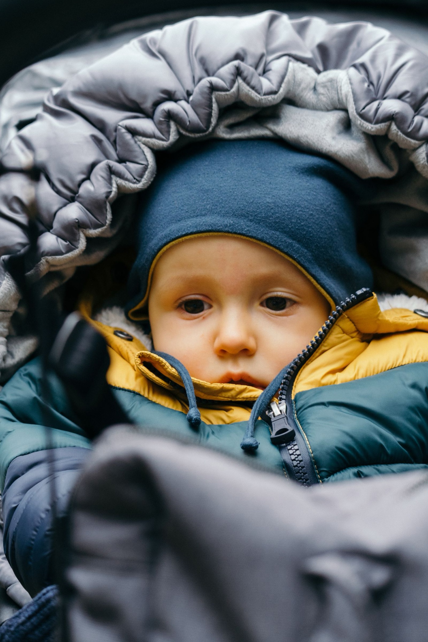Talvihaalariin ja lämpöpussiin puettu vauva istuu vaunuissa